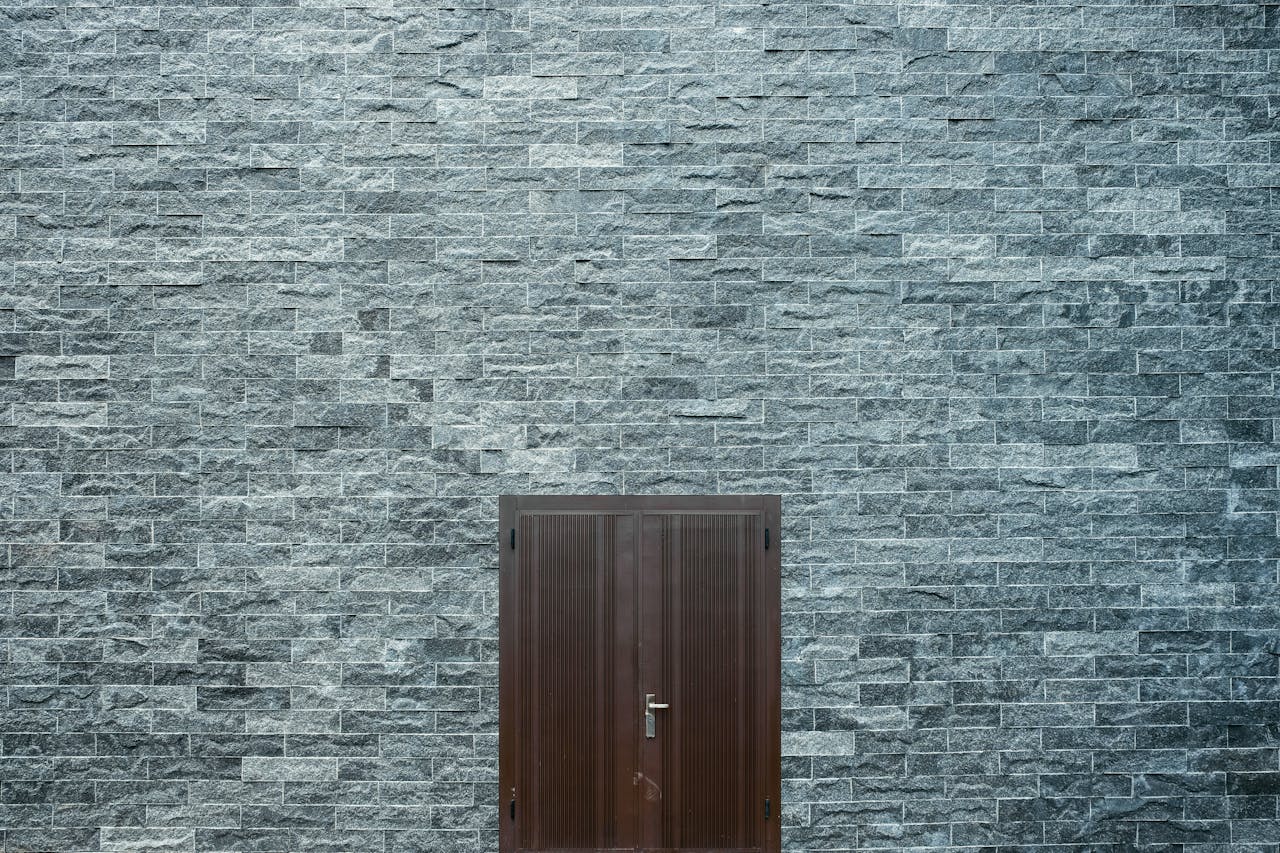 A minimalist stone brick wall featuring a simple wooden door, showcasing architectural design.
